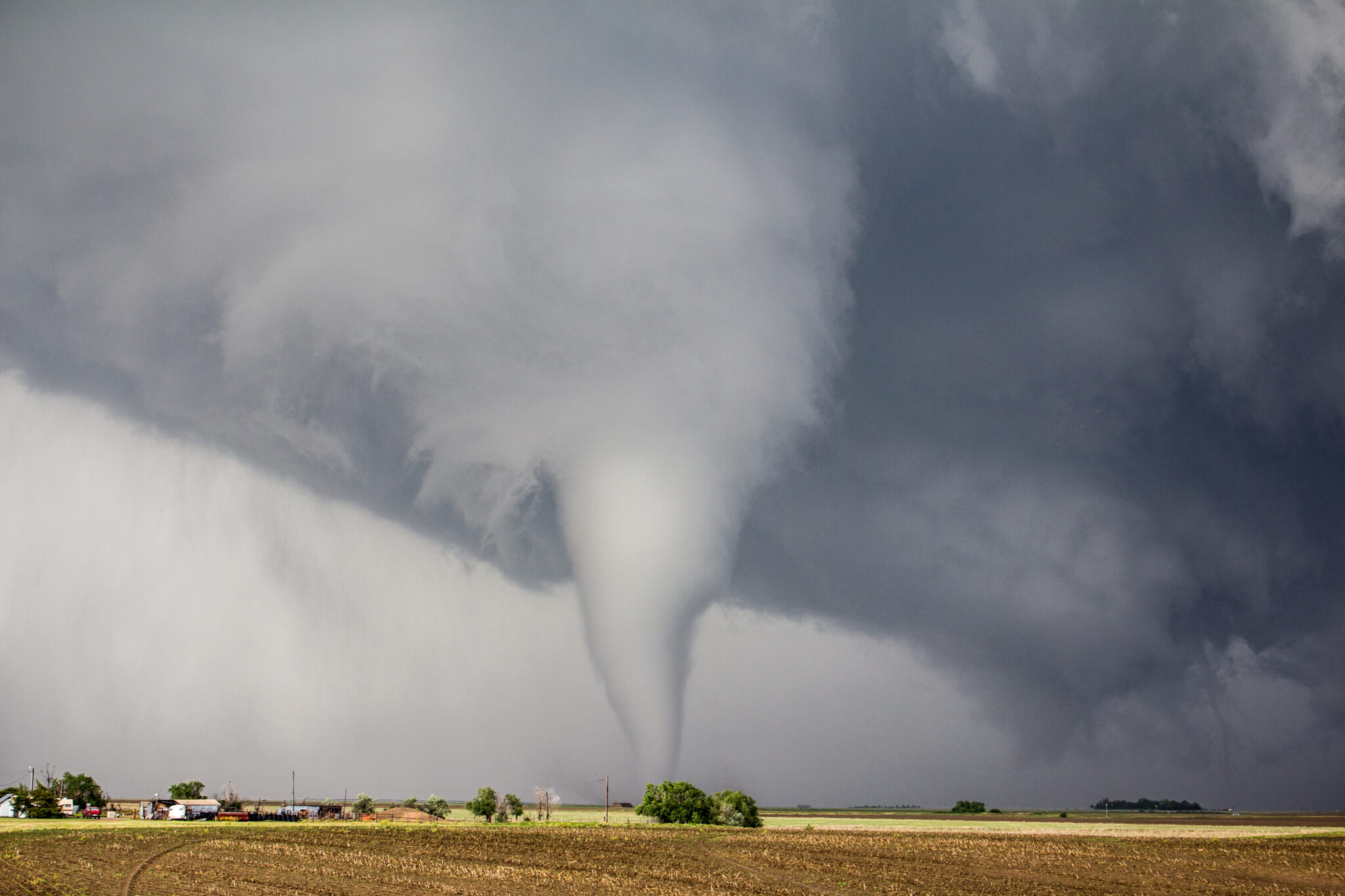 photo of a tornado in a field and dark storm clouds