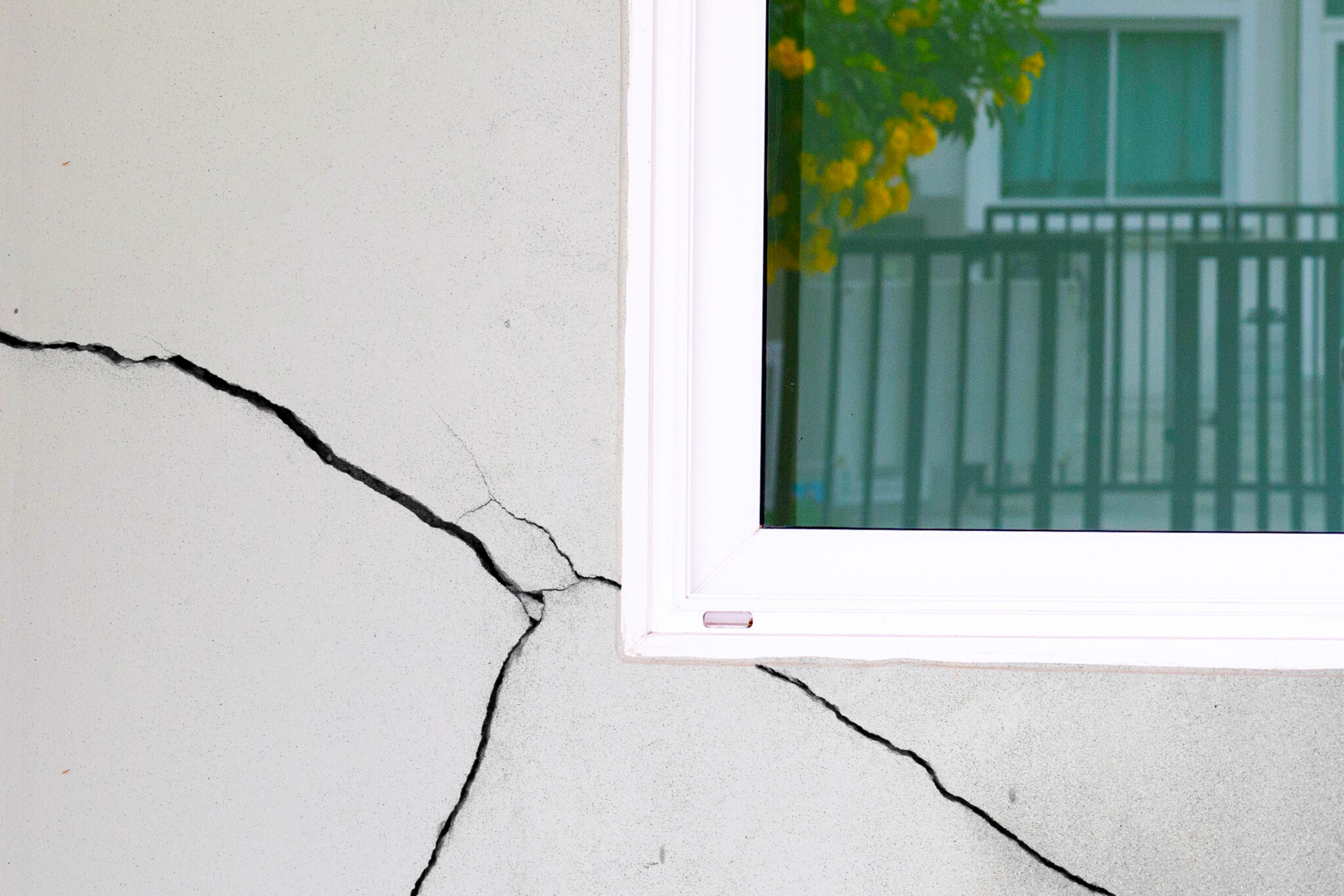 photo of a window on exterior of house with a crack in the wall