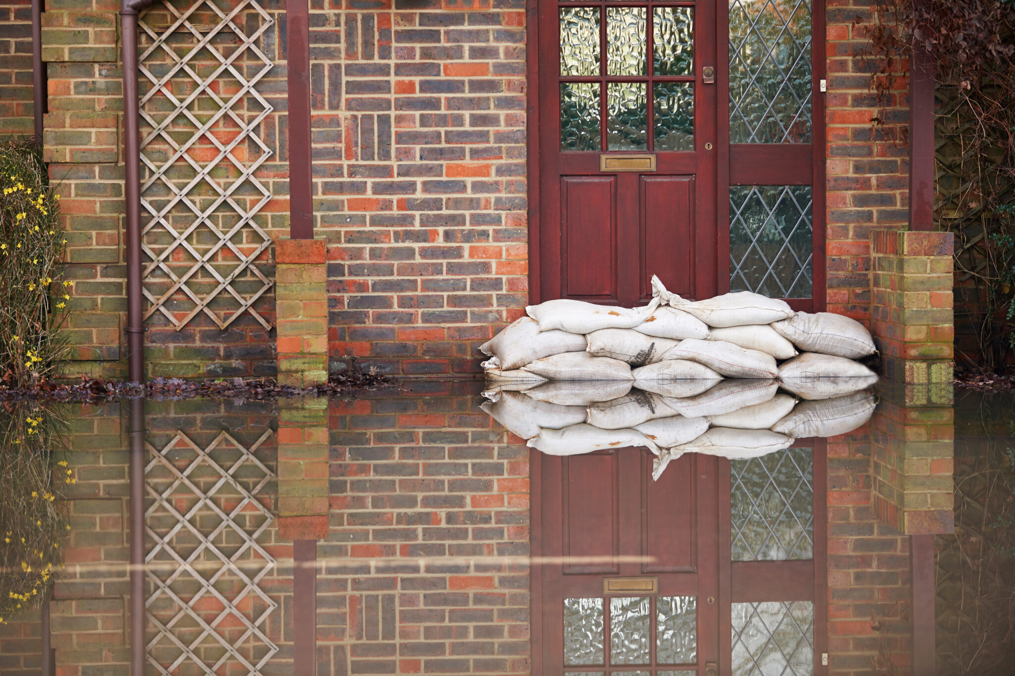 photo of exterior of a house with standing water and sand bags in front of exterior door
